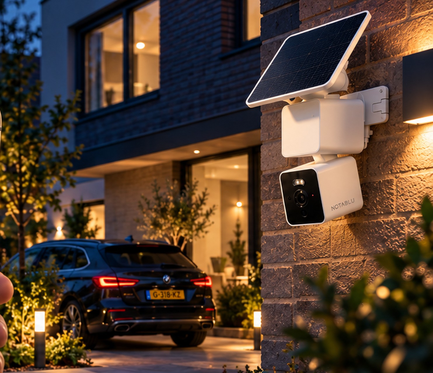 NOTABLU Solar Cam aan een Nederlandse bakstenen gevel, met auto op de oprit in de schemering